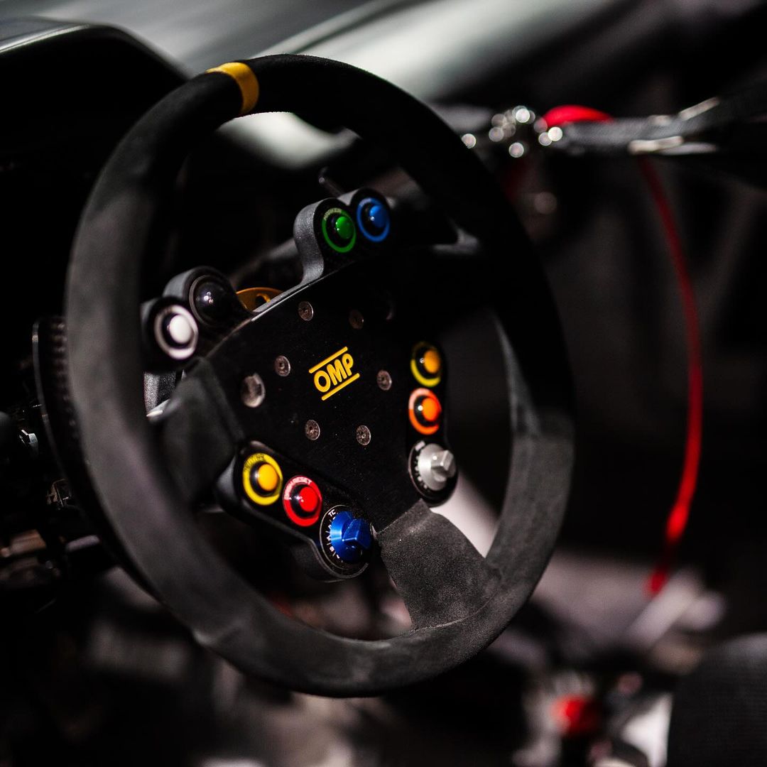 Close-up of a Volantech made racing steering wheel with colorful buttons in a car interior.